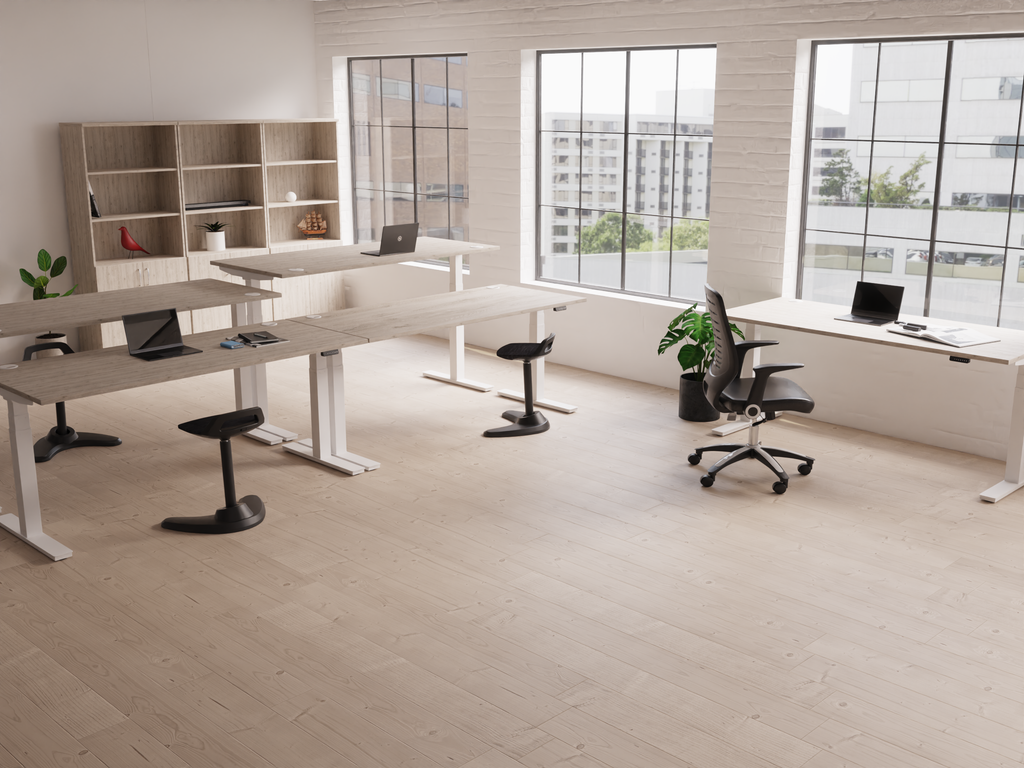 Air height adjustable sit stand desks in a bright office with seated and standing workstations